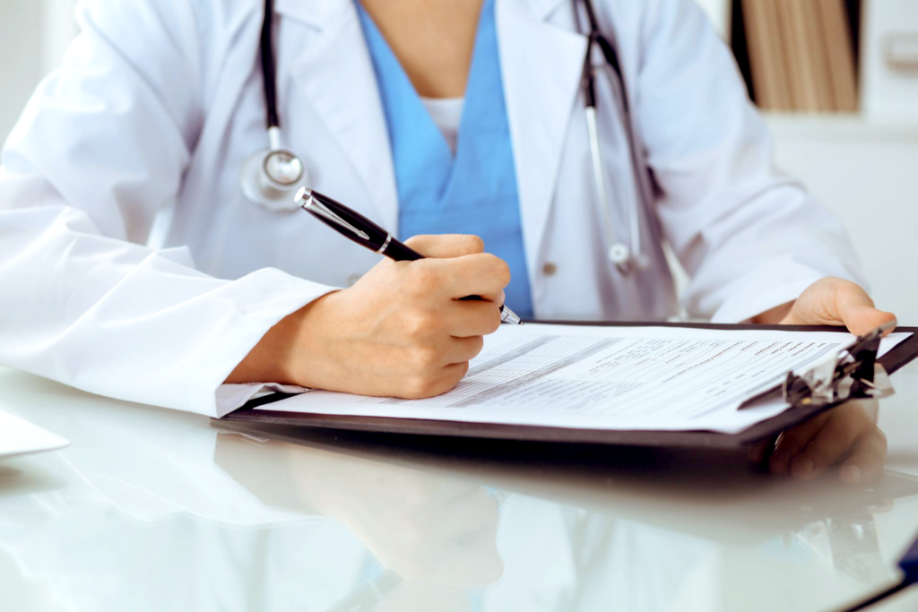 Medical personnel filling out form on a clipboard.