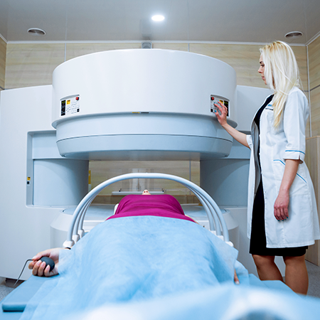 Patient on a scan table of an open MRI w/ a squeeze ball. MR personnel pressing a button on scanner.