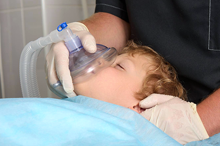 A young pediatric patient is given anesthesia through gas.