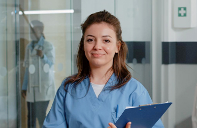 A female nurse with a clipboard smiling at camera.