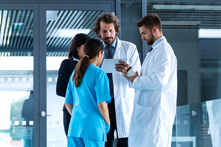 Four medical personnel are gathered around outside a medical facility.