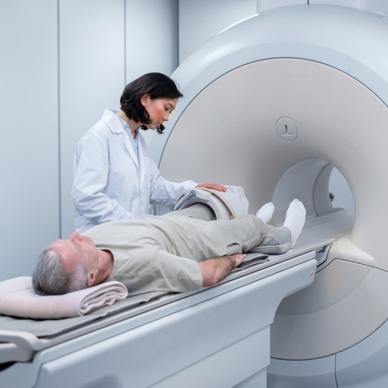 MR technologist performing an MRI knee scan on an older patient